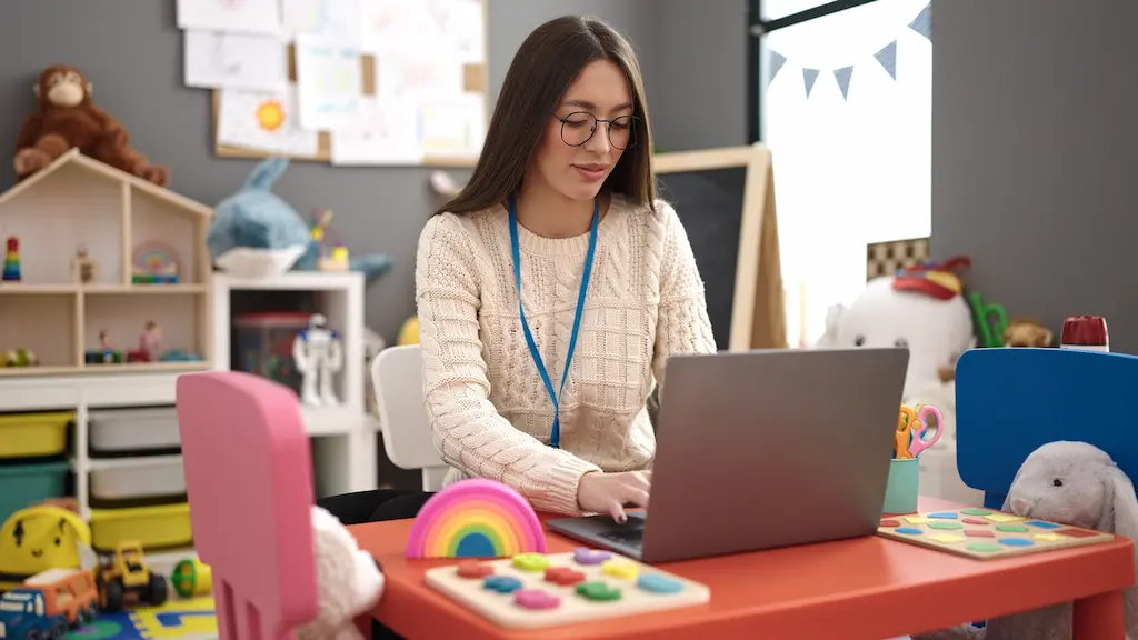 a teacher using a laptop to track student progress in a classroom